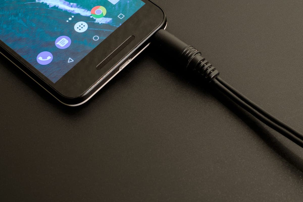A smartphone displaying a charging app beside a car