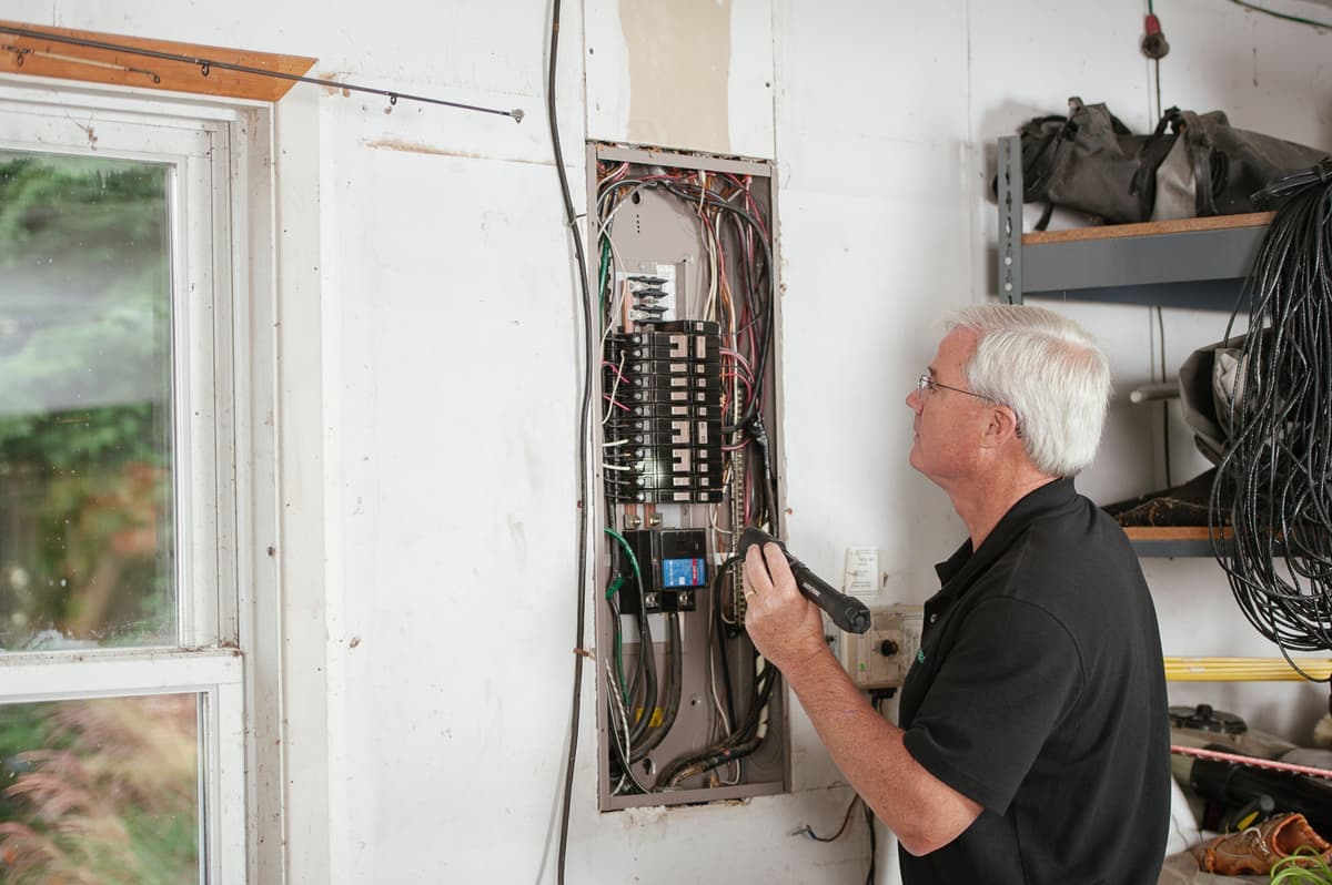An electrician working at an open residential breaker panel