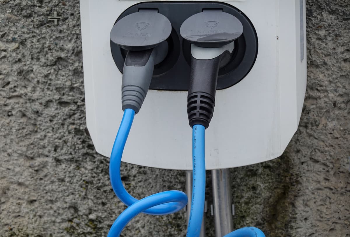 A portable EV charging cable coiled beside a car